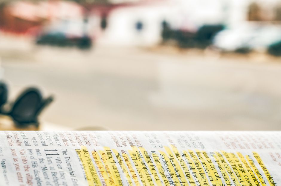 Close-up of an open Bible with highlighted text, blurred background for copyspace.